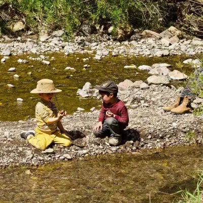 a group of people sitting on a rock next to a body of water