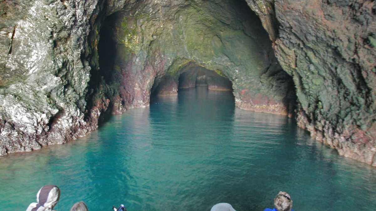 a group of people on a rock next to a body of water