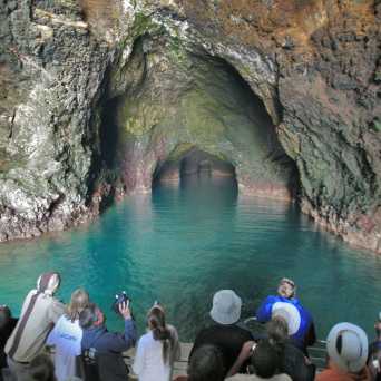 a group of people on a rock next to a body of water