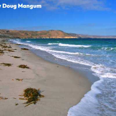 a sandy beach next to a body of water