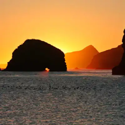 a sunset over a body of water with a mountain in the background